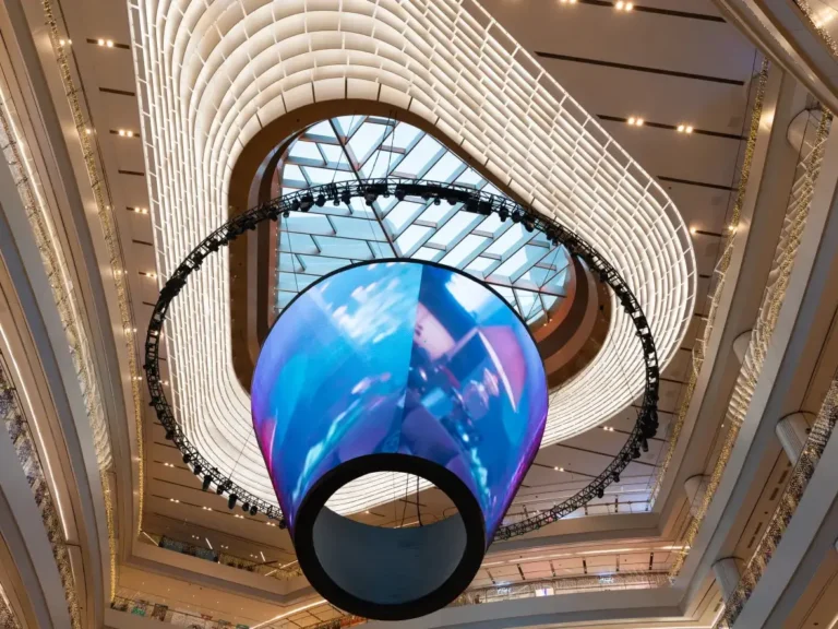 Adhaiwell custom cylindrical LED display suspended in a modern shopping mall atrium, creating an eye-catching interactive brand experience