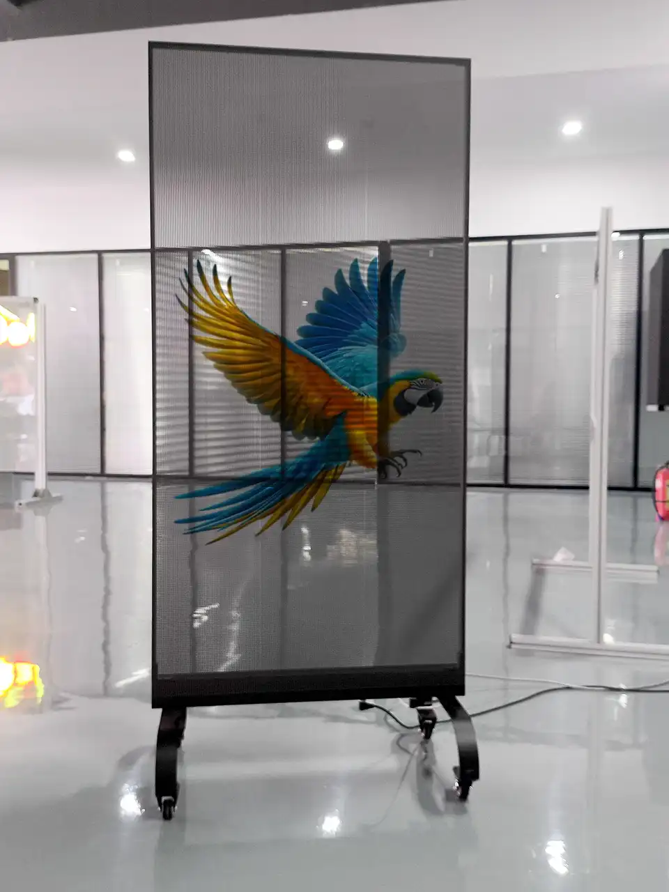 Holographic Transparent LED Film Screen 5 Adhaiwell standing holographic transparent LED screen with mobile wheels, showing clear mesh structure and frameless design for retail and exhibition use